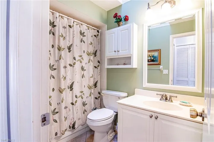 Bathroom with a shower with shower curtain, vanity, toilet, and tile patterned floors