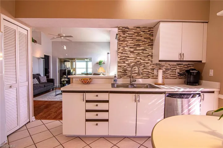 Kitchen featuring white cabinetry, sink, ceiling fan, stainless steel dishwasher, and backsplash