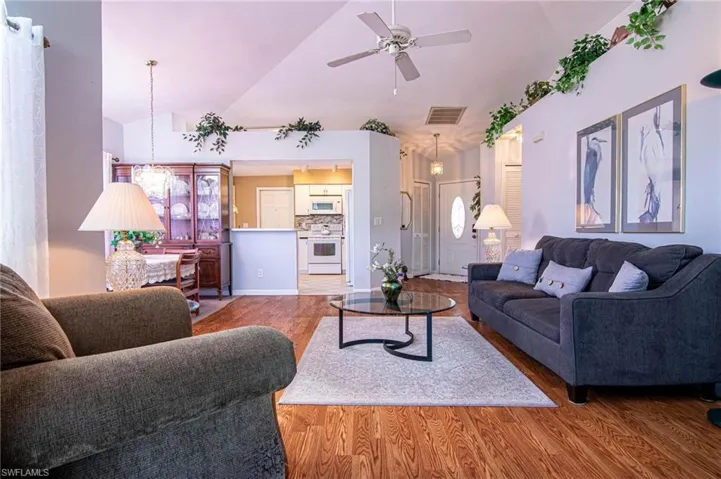 Living room with ceiling fan, wood-type flooring, and lofted ceiling