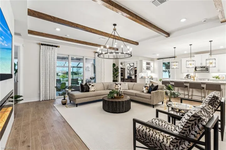 Living room with beam ceiling, a chandelier, a healthy amount of sunlight, and hardwood / wood-style flooring
