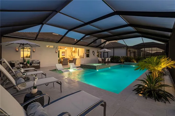 View of swimming pool featuring glass enclosure, an in ground hot tub, and a patio area