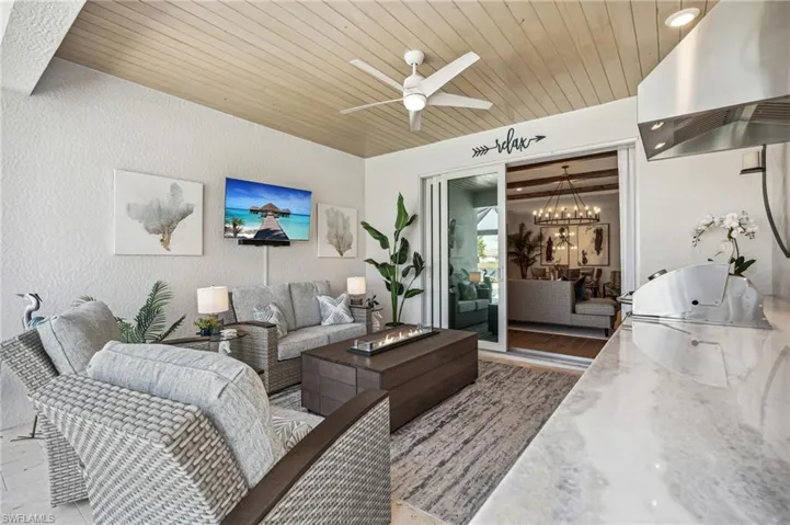 Living room with hardwood / wood-style flooring, ceiling fan with notable chandelier, and wooden ceiling