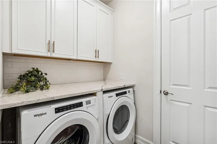 Clothes washing area featuring washing machine and dryer and cabinets