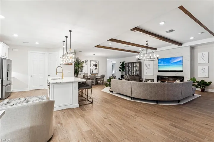 Living room with beam ceiling, sink, and light hardwood / wood-style flooring