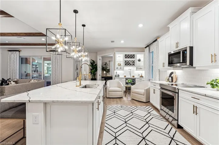Kitchen featuring pendant lighting, a kitchen island with sink, sink, white cabinetry, and stainless steel appliances