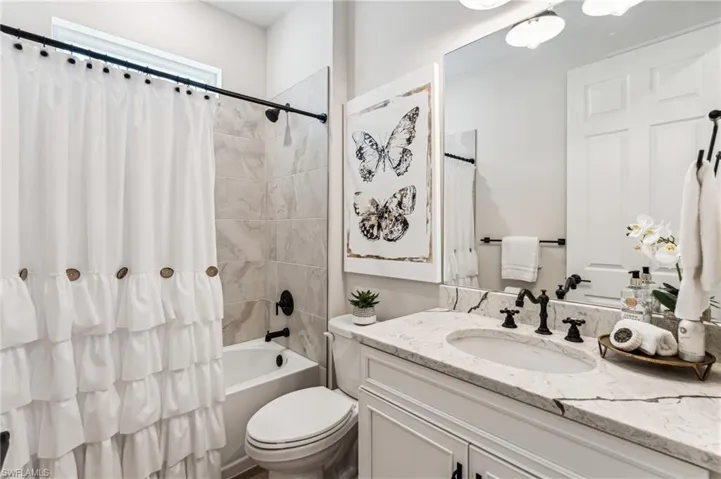 Full bathroom featuring vanity, shower / bath combination with curtain, and toilet