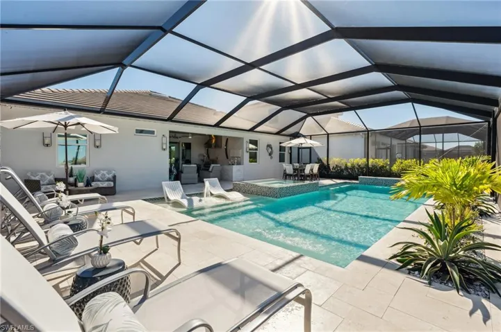 View of swimming pool featuring glass enclosure, an in ground hot tub, and a patio