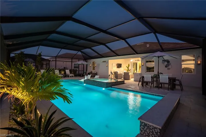 View of swimming pool with glass enclosure, an in ground hot tub, and a patio
