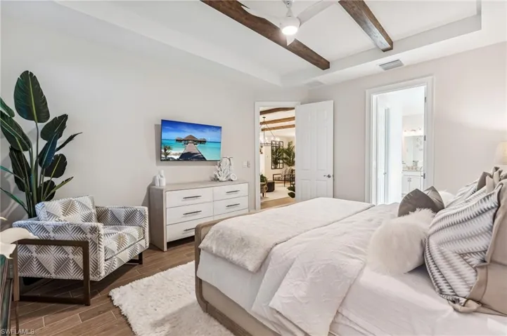 Bedroom featuring beam ceiling, connected bathroom, ceiling fan, and dark hardwood / wood-style floors