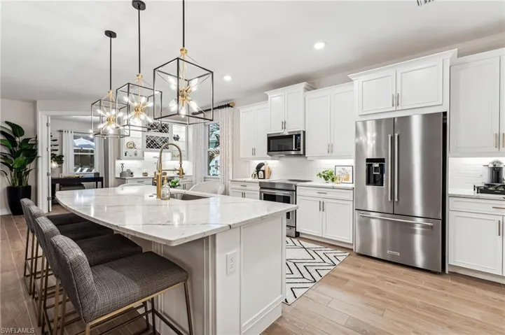Kitchen featuring appliances with stainless steel finishes, a center island with sink, and white cabinetry