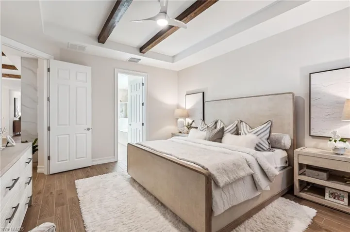Bedroom with beamed ceiling, ceiling fan, ensuite bathroom, and light hardwood / wood-style flooring