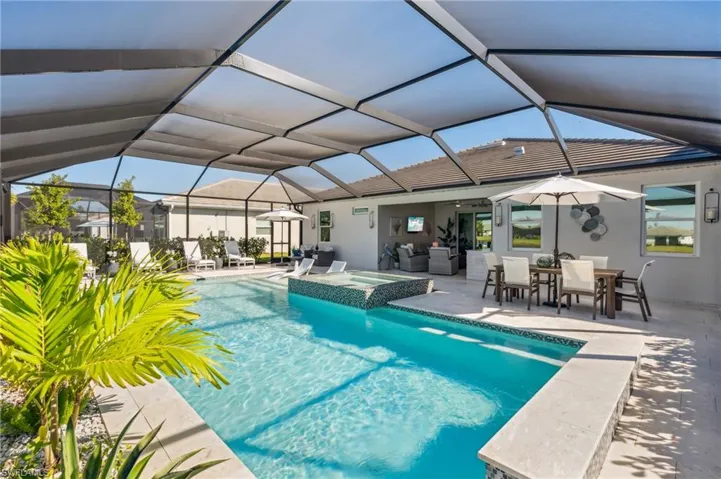 View of swimming pool featuring an in ground hot tub, a patio, glass enclosure, and ceiling fan