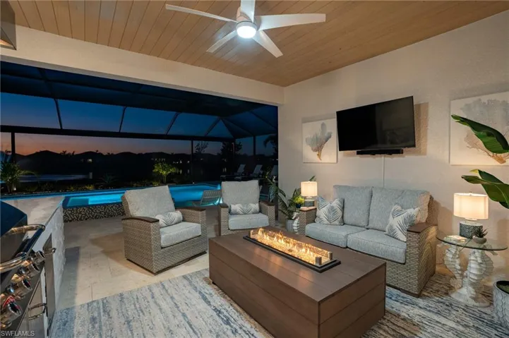 Patio terrace at dusk with ceiling fan, a lanai, and an outdoor living space with a fire pit