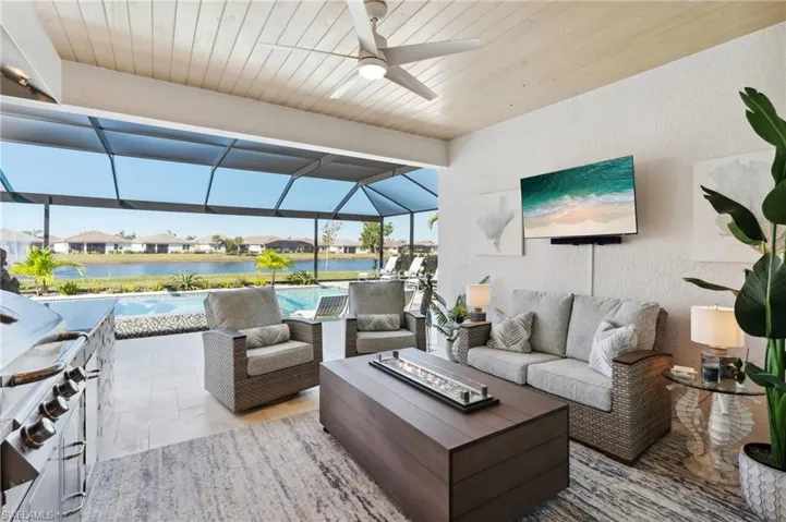 View of patio with ceiling fan, a lanai, and an outdoor living space with a fire pit