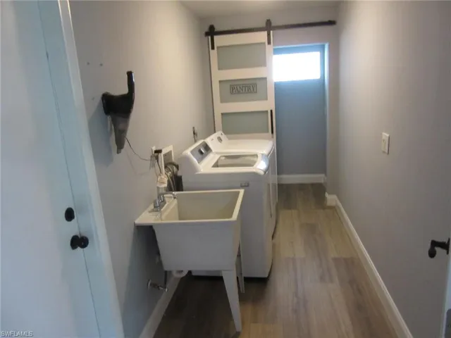 Washroom with light wood-type flooring, a barn door, and independent washer and dryer