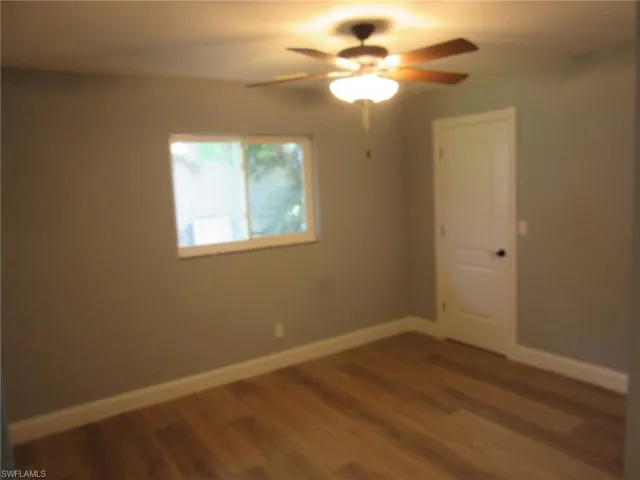 Unfurnished room featuring ceiling fan and dark wood-style flooring