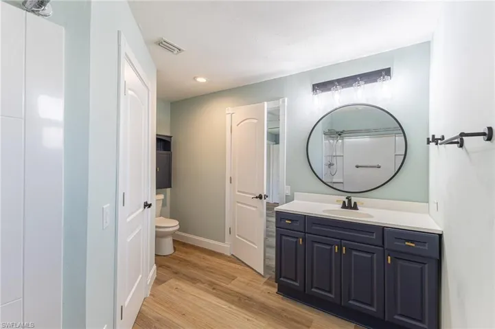 Full bath with vanity, light wood-style floors, and recessed lighting
