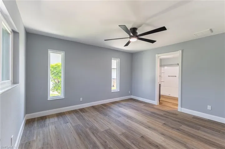 Unfurnished bedroom featuring wood finished floors, ceiling fan, and connected bathroom