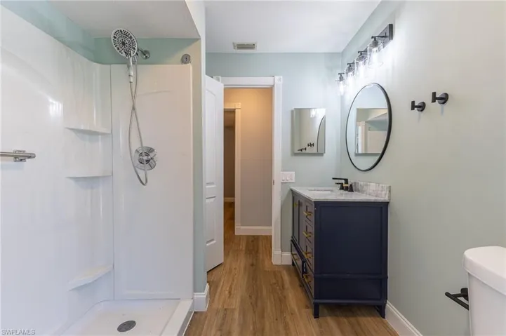 Full bath featuring vanity, a shower stall, and light wood-type flooring