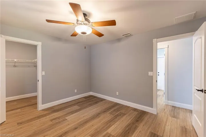 Unfurnished bedroom with light wood-style flooring, a walk in closet, and a ceiling fan