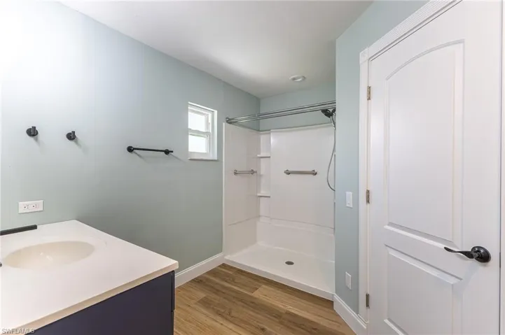 Full bathroom with a stall shower, vanity, and light wood-type flooring