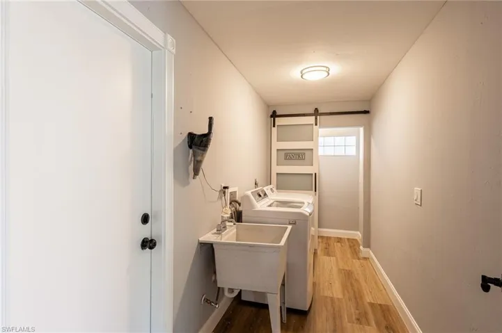 Laundry area featuring light wood-style floors, independent washer and dryer, and a barn door