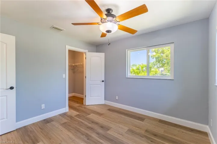 Unfurnished bedroom with wood finished floors, a walk in closet, and ceiling fan