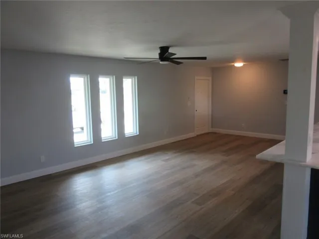 Unfurnished room with dark wood-type flooring and ceiling fan