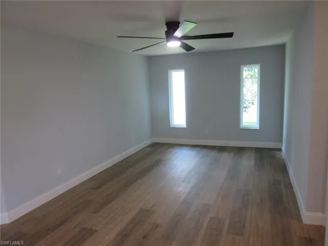 Unfurnished room featuring dark wood-style flooring and ceiling fan