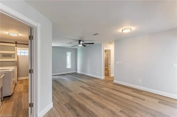 Empty room with a barn door, a ceiling fan, healthy amount of natural light, and light wood-style flooring