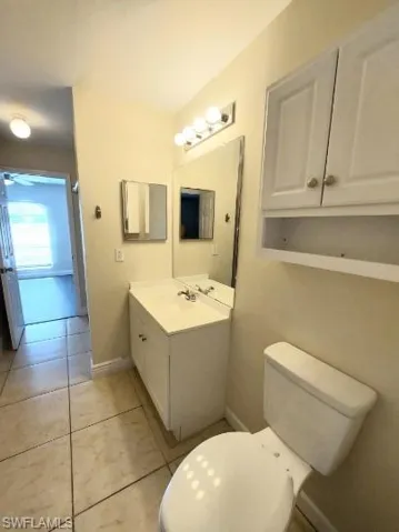 Half bath with light tile patterned flooring and vanity