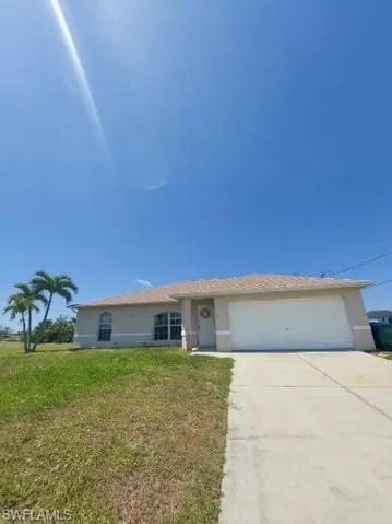 Single story home featuring stucco siding, a front yard, driveway, and an attached garage