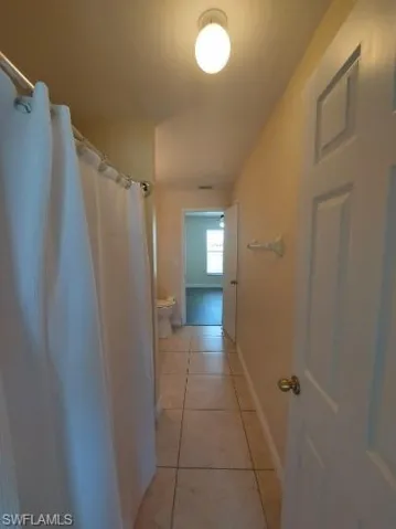 Hall with light tile patterned floors and baseboards