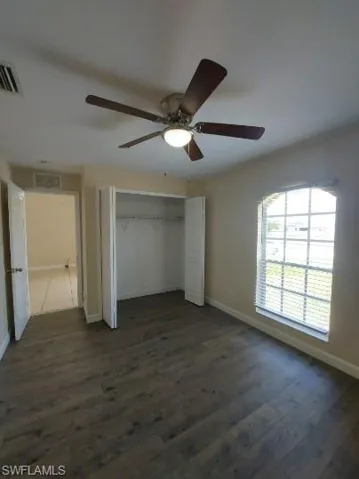 Unfurnished bedroom with a closet, dark wood-type flooring, and ceiling fan