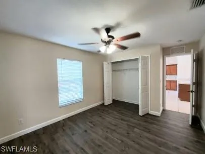 Unfurnished bedroom with dark wood-type flooring, ceiling fan, and a closet