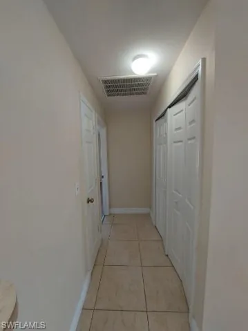 Corridor with light tile patterned floors and baseboards