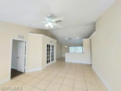 Spare room featuring lofted ceiling, light tile patterned floors, and ceiling fan