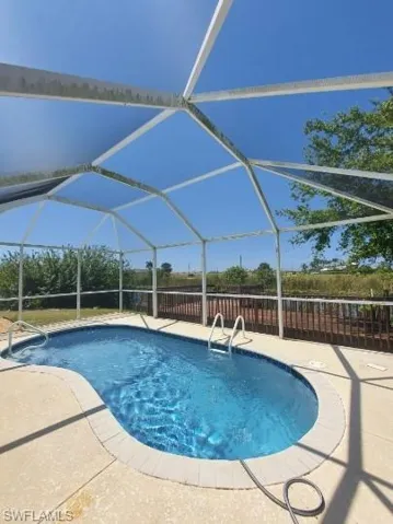 View of swimming pool with a lanai, a sunroom, and a patio