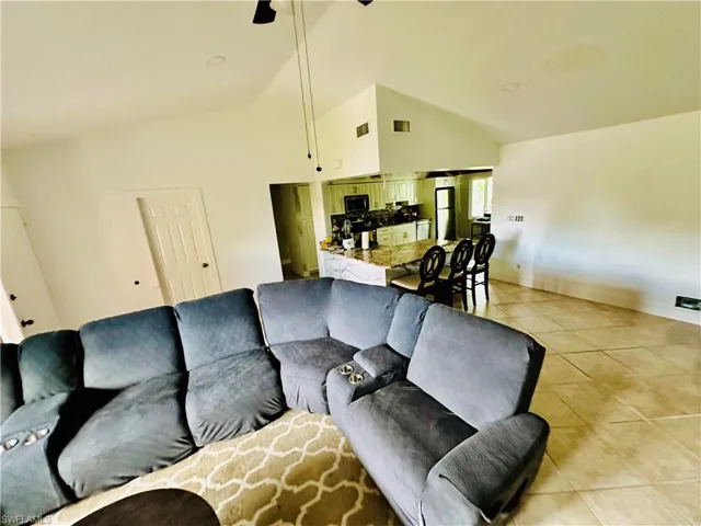 Tiled living room with high vaulted ceiling and ceiling fan