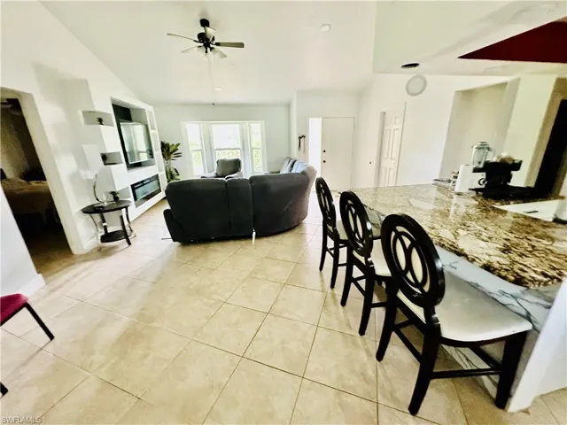 Dining room with vaulted ceiling, light tile patterned floors, and ceiling fan