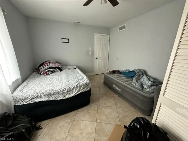 Tiled bedroom featuring ceiling fan