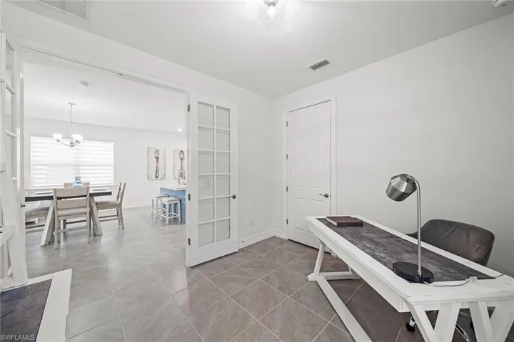 Office area featuring french doors, light tile patterned flooring, and a chandelier