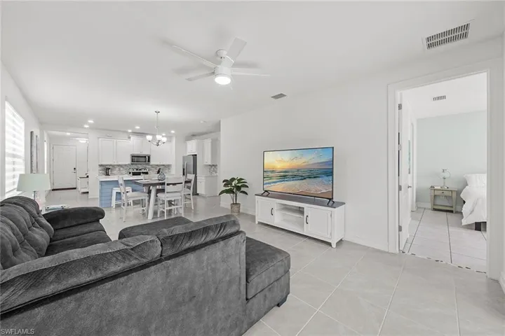 Living area with light tile patterned floors, ceiling fan, recessed lighting, and a chandelier