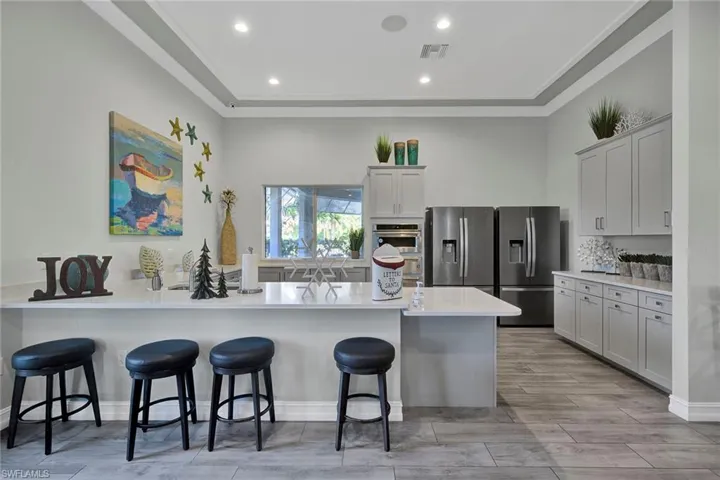 Kitchen featuring a kitchen breakfast bar, a peninsula, stainless steel appliances, light stone counters, and recessed lighting