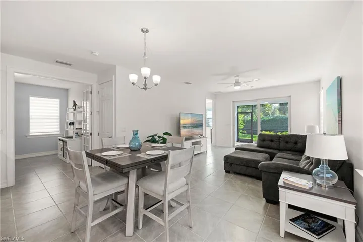 Dining room with light tile patterned floors, a chandelier, and a ceiling fan