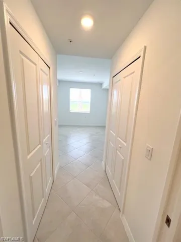 Hallway featuring light tile patterned floors and baseboards