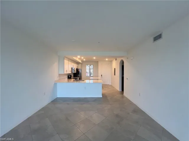 Kitchen with a peninsula, white cabinets, arched walkways, stainless steel appliances, and recessed lighting