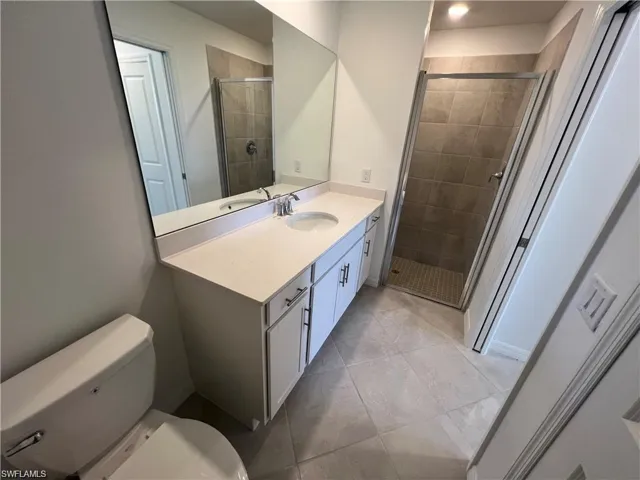 Full bathroom with a stall shower, vanity, and light tile patterned floors