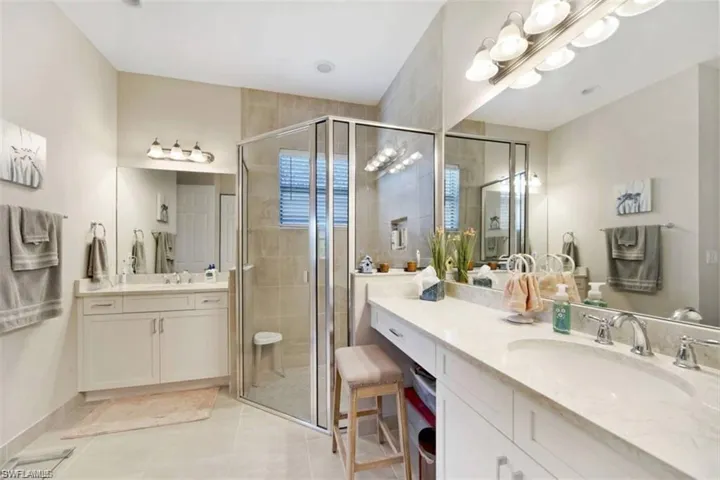 En suite bathroom with separate vanities, walk in shower, and linen closet