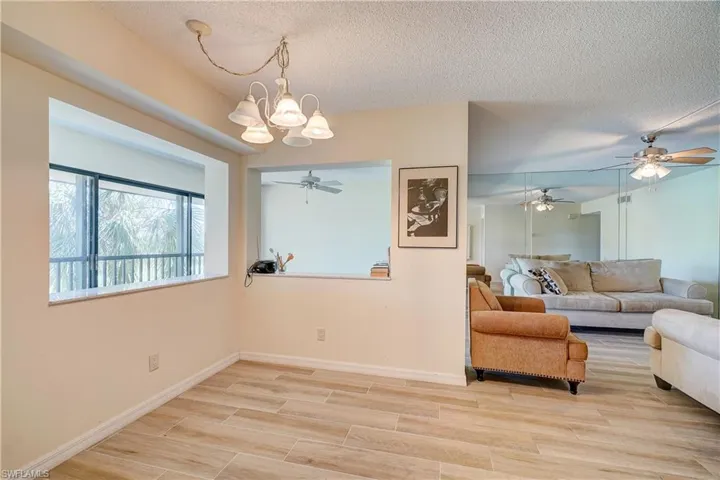 Living room with light hardwood / wood-style floors, a textured ceiling, and ceiling fan with notable chandelier